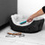 Hand using turquoise pet hair remover brush on grey sofa cushion