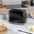 Black electric kettle with visible water gauge, Salter brand, finger switching it on