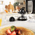 Black and silver electric citrus juicer with clear jug and handle, shown from front.