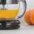 Glass Progress juicer jug with fresh orange juice, next to whole oranges.