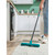 Person using blue rubber broom to clean rug in a modern white kitchen
