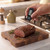 Digital meat thermometer checking doneness of roast beef on wooden board