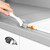 Hand using cleaning brush to remove food spill from kitchen sink edge