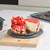 Strawberry cheesecake with a slice cut out on a plate, shown on a kitchen counter