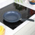 Grey speckled non-stick frying pan on induction hob, handle facing right