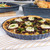 Round enamel pie dish with baked goat's cheese and spinach quiche, on kitchen worktop
