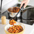 Serving pasta with tomato sauce from pan into bowl using black ladle
