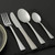 Set of four stainless steel cutlery pieces: fork, knife, dessert spoon, and teaspoon.