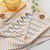 Set of six silver dessert spoons on a patterned tea towel, lifestyle setting