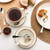 Overhead view of two cups and saucers with tea, Victoria sponge cake, and jam.