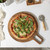 Stone-baked pizza with rocket on wooden board, overhead view