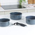 Set of three grey speckled saucepans with detachable black handle on kitchen worktop