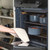 Blue speckled casserole dishes in oven, hand removing with oven glove