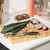 Bamboo chopping board with knife, kale leaves, garlic and sliced red onion on kitchen counter