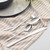 Four-piece silver cutlery set with fork, knife, and two spoons on patterned cloth.