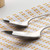Pair of stainless steel spoons on white and yellow textured tea towel
