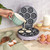 Mini doughnut maker with freshly baked doughnuts, spatula lifting one, on kitchen counter