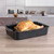 Non-stick roasting tin with rack holding cooked chicken, shown in a modern kitchen