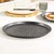 Black speckled round pizza tray shown empty on kitchen counter
