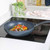 Speckled non-stick frying pan with stir-fried peppers and onions on induction hob