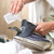 Hand filling steam iron with water, focus on spout and controls