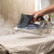 Hand using Beldray steam iron on beige fabric, steam visibly removing creases