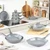 Set of grey non-stick pans, frying pans, and grill pan on modern kitchen worktop