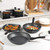 Set of black non-stick cooking pans with food, shown from above on kitchen worktop