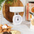White mechanical kitchen scale on worktop, bowl on top, shown in a home baking setting