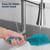 Turquoise silicone cleaning brush held under running tap in kitchen sink