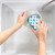 Hand washing a white pet bowl with blue paw prints in a kitchen sink