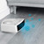 Portable white fan heater blowing cool air with blue snowflake icons, shown on grey floor.