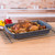 Blue speckled roasting tray with whole roast chicken and vegetables on kitchen counter