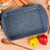 Blue speckled roasting tray on wooden surface with assorted vegetables nearby