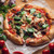 Assorted pizzas including vegetable and meat toppings, served with salad, top-down view