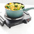 Single electric hot plate with a teal saucepan cooking pasta and vegetables