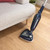 Navy steam mop cleaning wooden floor beside beige sofa