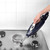 Handheld steam cleaner being used on stainless steel gas hob