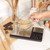 Baking scales with glass bowl of brown sugar, hand shown, kitchen counter scene.