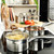 Stainless steel saucepan with tomato sauce on induction hob, fresh tomatoes in background