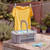 Grey peg basket and pastel pegs on outdoor table, yellow T-shirt drying on line behind