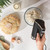 Black electric hand mixer with chrome whisk attachment, side view