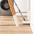 Flat mop cleaning light wood kitchen floor under table, washing machine in background