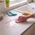 Hand using pink sponge cloth to wipe kitchen worktop by sink