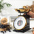 Black mechanical kitchen scale with gold bowl, shown side-on