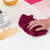 Hand using red cloth to clean coffee spill from white surface