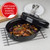 Black oval roasting tin with easy-clean enamel coating, lid, with cooked chicken and vegetables.