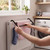 Black radiator airer holding laundry in a utility room, hands placing blue sock to dry