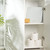 Bathroom shelf with three toilet rolls, sea sponge, and Salter bathroom scale.
