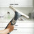 Handheld window vacuum cleaner being used on glass in a bathroom